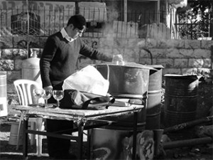 A man stands with large containers of boiling water, ready to kasher (make kosher) untensils for Pesach use. This photo was taken in Meah Sha'arim, a religious area of Jerusalem where apartments are often small and crowded with no storage space available for utensils reserved just for Pesach use.