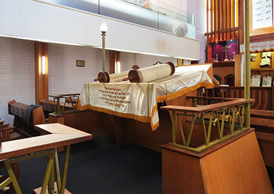 An open Sefer Torah (Torah scroll) lies on the reading desk on the bimah in this synagogue