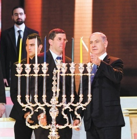Prime Minister Netanyahu of Israel lighting a chanukiiah on 8th night Chanukah. He uses the shamash light (which, in this chanukiah, will be placed in the central location and higher than the other lights to distinguish it from them) to ignite all the other lights.