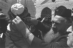 A 3 year old boy receives his first haircut at Meron on Lag baOmer