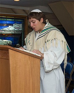 A man leading a prayer service on Yom Kippur and wearing a kittel (white robe) and tallit (prayer shawl). The kittel is worn over the man's ordinary clothes.